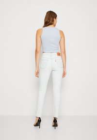 Világoskék cropped top, fehér, finom mosású skinny farmernadrággal, hátsó zsebekkel és barna bőrcímkével a derékpánton.