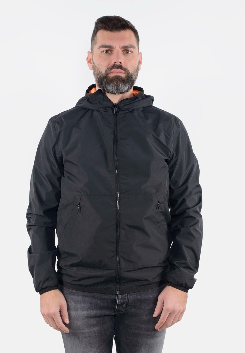Giacca nera con zip e cappuccio, realizzata con una texture liscia e dettagli arancioni all'interno, dotata di tasche laterali e polsini elasticizzati.