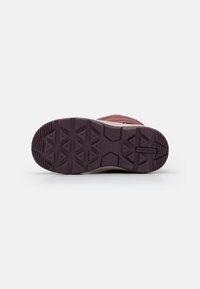 Burgundiszinű sneaker talp, texturált gumival a jobb tapadás érdekében, háromszög alakú profillal és az oldalán lévő logó címkével.
