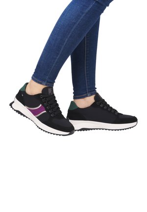 Black sneakers with purple and white accents, textured fabric, lace-up design, and a white outsole feature. Worn with dark blue jeans.