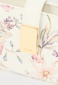 Cartera con estampado floral en material blanco texturizado, con un cierre dorado grabado con "ALDO". Los detalles incluyen flores rosas y azules.