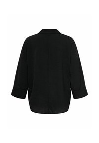 Črna oversize srajca s strukturnim ovratnikom, rokavi do tri četrtine in teksturirano tkanino. Brezšivna zadnja zasnova brez zapiranj.