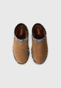 Chaussures slip-on en daim marron avec un bord en tissu multicolore texturé. Design à bout arrondi et doublure intérieure douce visible de la vue de dessus.