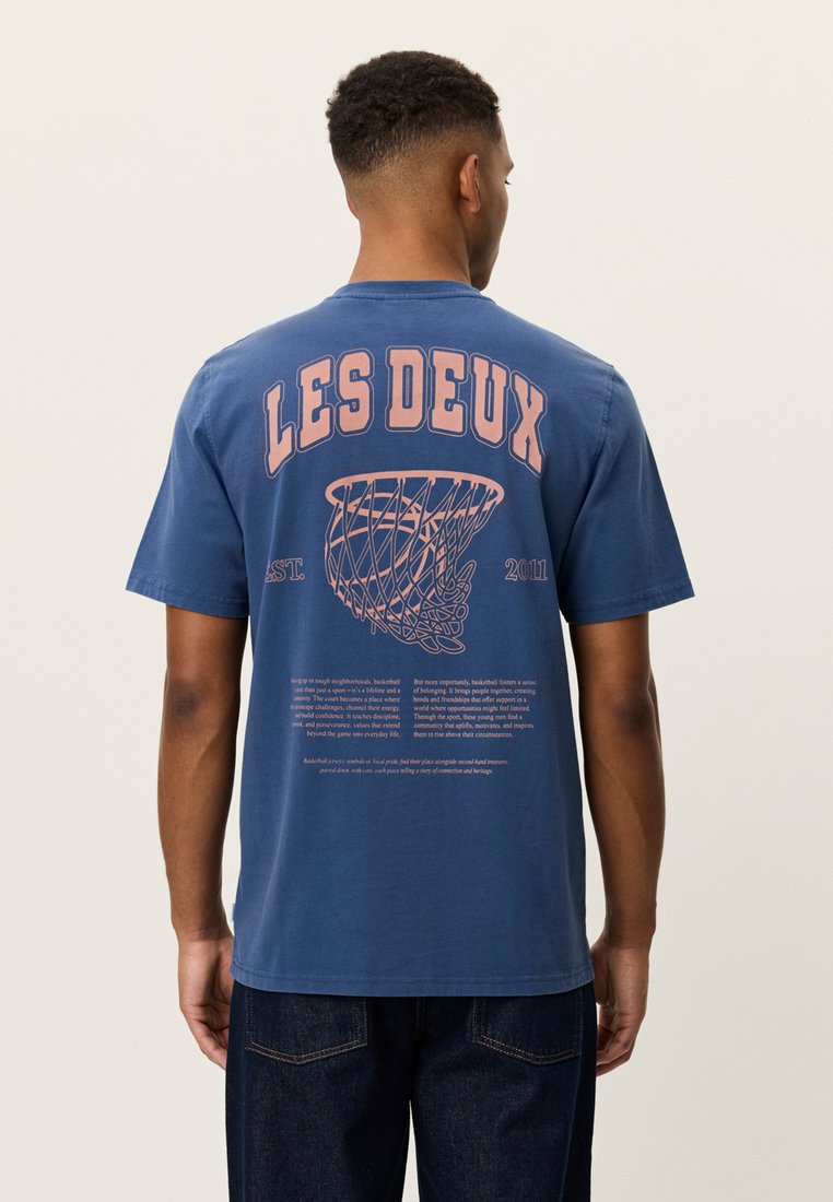 Μπλε βαμβακερό t-shirt με γραφικό δίχτυ καλαθοσφαίρισης και κείμενο στην πλάτη. Με κοντά μανίκια και άνετη γραμμή.