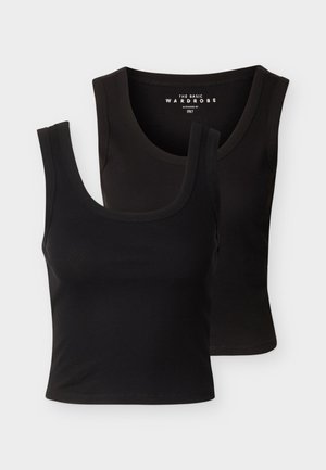 To svarte ermeløse ribbestrikkede tanktopper med rund hals, den ene litt plassert bak den andre mot en ensfarget hvit bakgrunn.