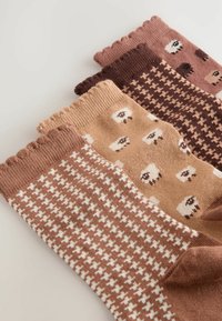 Vier paren gezellige sokken in tinten bruin, met verschillende patronen zoals schapen en houndstooth, tentoongesteld op een lichte achtergrond.