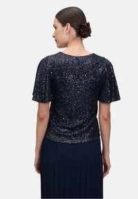 Granatowa górna część z cekinami, z krótkimi, falbaniastymi rękawami, z okrągłym dekoltem i dopasowanym topem, noszona na plisyowanym spódnicy.