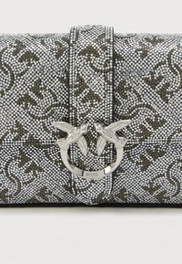 Τσάντα χειρός με ασημένια καρφιά στην επιφάνεια και σκούρο σχέδιο. Κλείσιμο με διπλό υλικό σε σχήμα πουλιού. Υφή στην επιφάνεια.