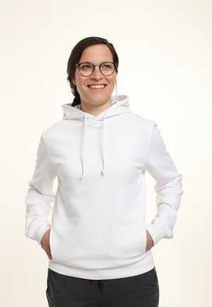 Felpa bianca con tasca frontale, cappuccio con coulisse e maniche lunghe, indossata sopra pantaloni grigio scuro. Tessuto liscio.