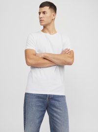 Hvid bomulds-t-shirt med rund halsudskæring, korte ærmer og en normal pasform, parret med lyseblå denim jeans. Simpelt design, ingen mønstre.