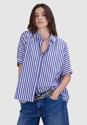 Blauw-wit gestreepte overhemden met korte mouwen, een borstzak en een relaxte pasvorm, gecombineerd met donkerblauwe jeans en een studsriem.