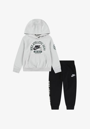 Sudadera gris con bolsillo frontal y texto gráfico, combinada con pantalones jogger negros que tienen un logo y texto en el lado. Ambos son de mezcla de algodón.