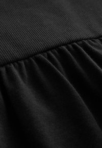 Material negru cu o secțiune superioară striată și o secțiune inferioară plisată, textură netedă, culoare uniformă pe toată suprafața.