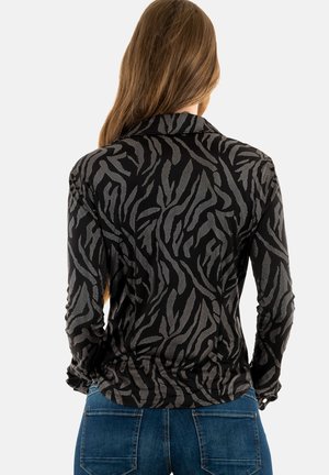 Maglietta nera a maniche lunghe con un motivo astratto argento, con una silhouette aderente e polsini arricciati. Tessuto liscio con una leggera lucentezza.