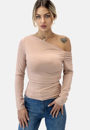 Lichtroze lange mouwen top met een asymmetrische halslijn en geplooide details, gecombineerd met blauwe jeans. Gladde textuur, getailleerd ontwerp.