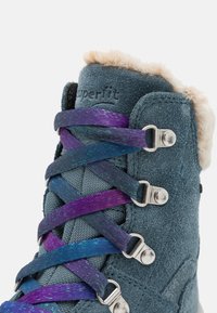 Botas de ante azul con un cuello de piel sintética, presentan cordones iridiscentes multicolores, ojales plateados y un acabado texturizado.
