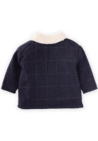 Mörkblå jacka med en vit konstskinnskrage, med ett rutmönster. Korta ärmar och en boxig passform. Mjuk textur, avslappnad design.