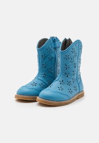 Blå lädercowboystövlar med utskurna blommönster, spetsig tå och strukturerad yta. Låg tan gummisula och blixtlås på sidan.