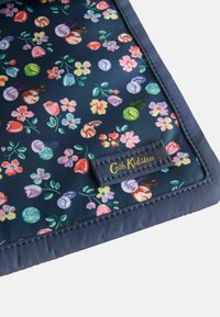 Jūrinės gėlės audinys, kuriame yra įvairiaspalvių gėlių ir sūkurėlių. Siuvinėta jūrinė kraštinė ir auksinė "Cath Kidston" etiketė apatinėje kampe.