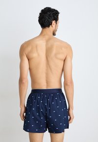 Navy blue boxer shorts made of lightweight fabric, featuring a small all-over pattern, elastic waistband, and a relaxed cut.