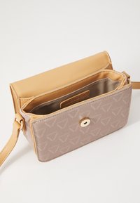 Světle růžová syntetická kabelka s hladkým povrchem, zlatými kovovými doplňky a značkovým štítkem uvnitř. Obsahuje magnetický uzávěr a nastavitelný popruh.