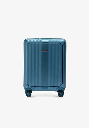 Valigia rigida con finitura teal metallica, caratterizzata da un motivo a righe verticali, superficie liscia e quattro ruote piroettanti per la mobilità.