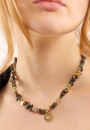 Collier perlé en or et gris foncé avec des formes de pierres irrégulières, des accents scintillants, et un charme circulaire avec une pierre précieuse transparente.