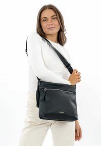 Sorte læder crossover taske med en tekstureret overflade, der har en lynlåslomme foran og en justerbar rem. Enkel, funktionel design.