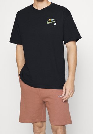 Czarny T-shirt z krótkim rękawem z wielokolorowym logo Nike na piersi, zestawiony z jasnobrązowymi szortami z białym logo.