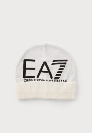 Valge kootud beanie koos volditud kreemivärvi äärega, millel on julge must logo ja triibud. Pehme tekstuur, ümar kuju pähetarviku jaoks.