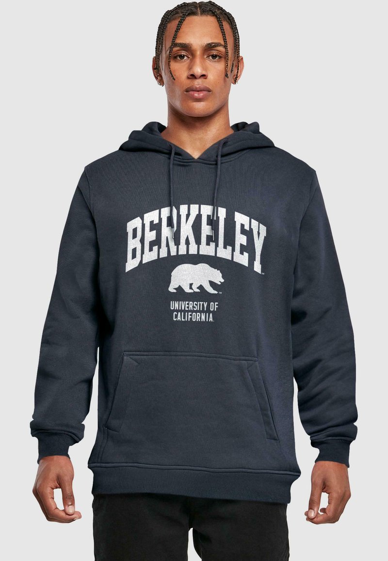 Tumed sinine kapuutsiga pluus, mis on valmistatud puuvillast segust. Ees on känguru tasku, valgete trükitud "BERKELEY" tekst ja karu logo rinnal.