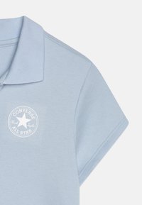 Lichtblauw korte mouwen polo shirt met opgerolde kraag en wit Converse All Star logo op de borst.