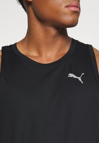 Débardeur sportif noir à surface texturée, col rond, avec un logo Puma gris sur le côté gauche de la poitrine. Sans manches.