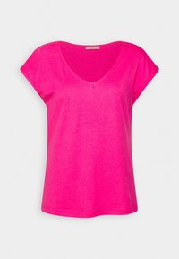 T-shirt femme rose vif à manches courtes, col en V et coupe ample, présenté sur un fond clair uni.