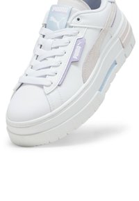 Sneaker PUMA in pelle bianca con accenti lilla chiaro, dotate di linguetta imbottita, lacci e una suola spessa e testurizzata. Dettaglio blu traslucido.
