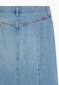 Falda de mezclilla azul claro con un diseño recto, que presenta una costura central, un refuerzo en las costuras y una pequeña etiqueta roja de "Levi's" en la parte posterior.