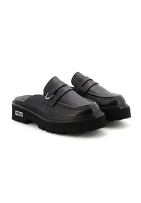 Scarpe slip-on in pelle nera con punta arrotondata, caratterizzate da ampie cinghie e una suola spessa con battistrada testurizzato, accentuate da un dettaglio in metallo a forma di anello.