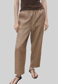 Pantaloni in lino marrone chiaro con vestibilità rilassata, dotati di una cintura elastica e cordino, texture liscia e design a gamba ampia.