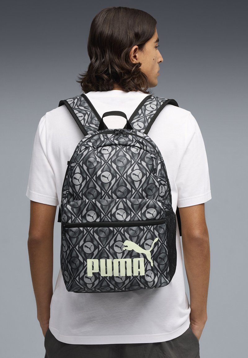 Schwarzer und grauer Rucksack mit einem auffälligen Puma-Logo. Verfügt über verstellbare Träger und eine strukturierte Oberfläche. Reißverschluss oben.