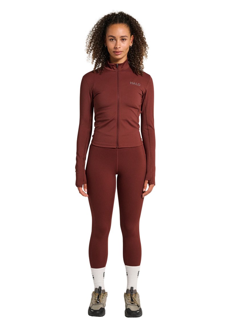 Bordeaux atletisk outfit med en zip-up jacka och åtsittande leggings. Slät textur, långärmad, och logotypdetalj på bröstet.