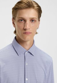 Hemd mit Knöpfen in einem blau-weißen geometrischen Muster, einem klassischen Kragen, glatter Textur und einer klassischen Passform mit Knopfverschluss.