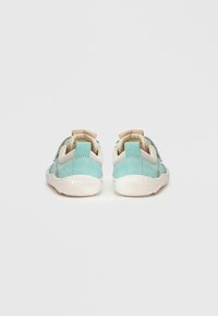 Paire de baskets pour enfants bleu clair et beige avec semelles blanches, vues de dos sur un fond neutre.