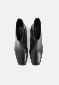 Mustad nahast pahkluu saapad ruudukujulise varbaosaga, sileda tekstuuriga ja külgmiste tõmblukkudega. Minimalistlik disain, millel on stiilne ja kaasaegne siluett.