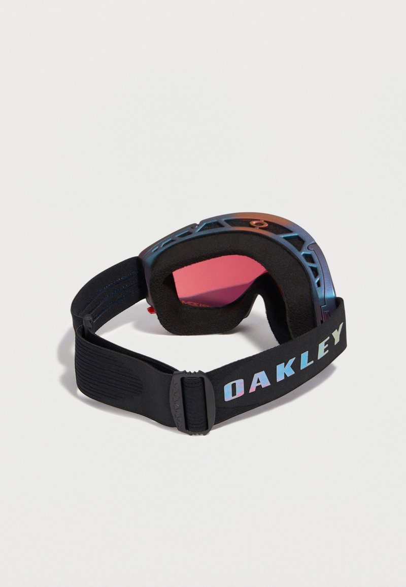 Zwarte Oakley skibril met roze getinte lens, schuimvoering en verstelbare elastische band met Oakley-logo op een witte achtergrond.