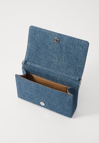 Borsa a pochette in denim con patta frontale e chiusura a scatto. Interno foderato in pelle marrone con logo del marchio. Include una tracolla in catena argentata.