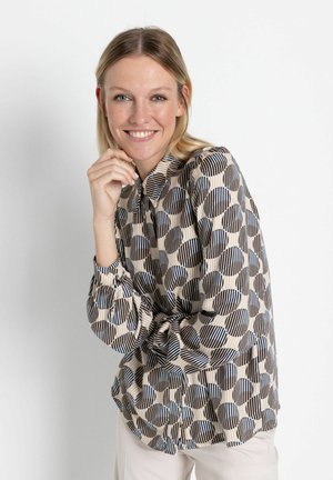 Langärmlige Bluse mit einem geometrischen Muster aus Kreisen und Streifen in Beige, Marineblau und Schwarz, mit einem Knopfkragen und gerafften Manschetten.