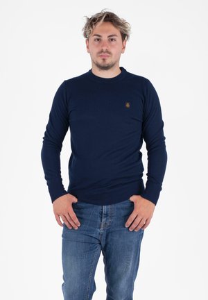 Marineblauwe gebreide trui met een ronde hals. Beschikt over geribbelde boorden en onderkant, samen met een klein merklogo op de borst. Standaard pasvorm.
