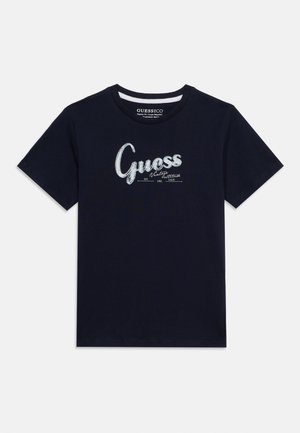 Marineblå t-skjorte med korte ermer og rund hals, med hvit tekst "Guess Vintage Attitude EST 1981 CALIF" på forsiden.