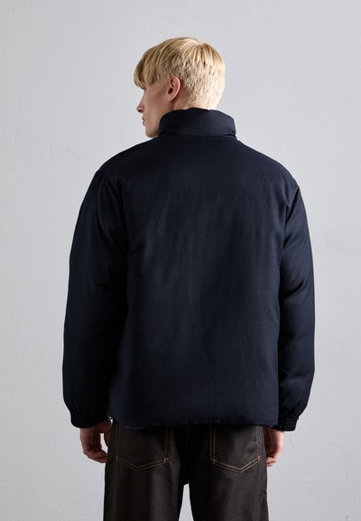 Black padded jacket with a high collar, elastic cuffs, and a smooth texture. Features a casual, oversized design, viewed from the back.