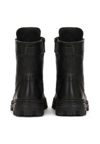 Botas de cuero negras hasta el tobillo con un acabado suave, cremalleras traseras y suelas de goma texturizadas; con un collar acolchado en la parte superior para mayor comodidad.